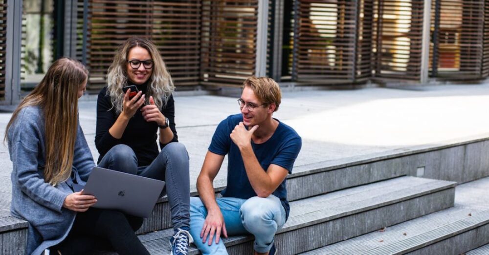 Students - Three Persons Sitting on the Stairs Talking With Each Other