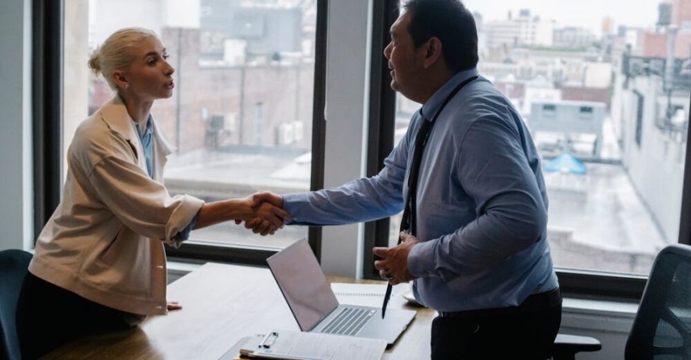 Career Opportunities - Young woman shaking hands with boss after business presentation