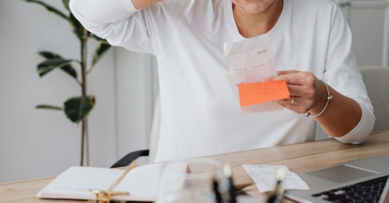 Costs - Woman at Desk Looking at Receipt and Scratching Her Head