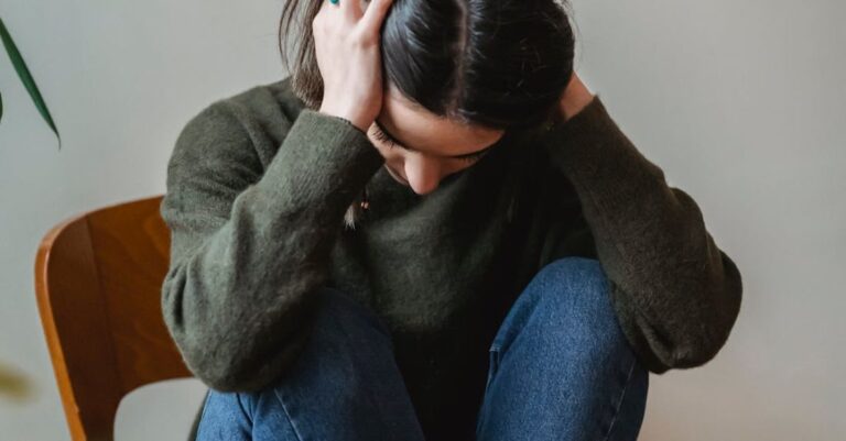 Ethical Concerns - Anxious young woman cover wing ears with hands sitting on chair