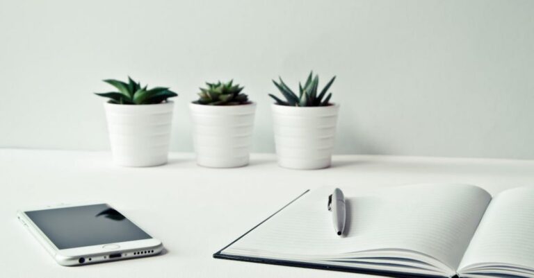 Companies - Three White Ceramic Pots With Green Leaf Plants Near Open Notebook With Click Pen on Top